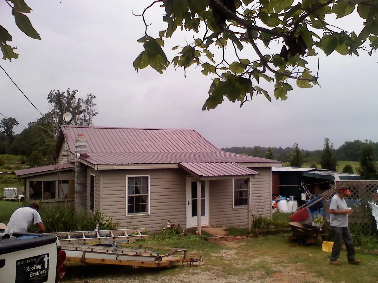 Crew finishing a mauve metal roof on a small farmhouse in De Soto